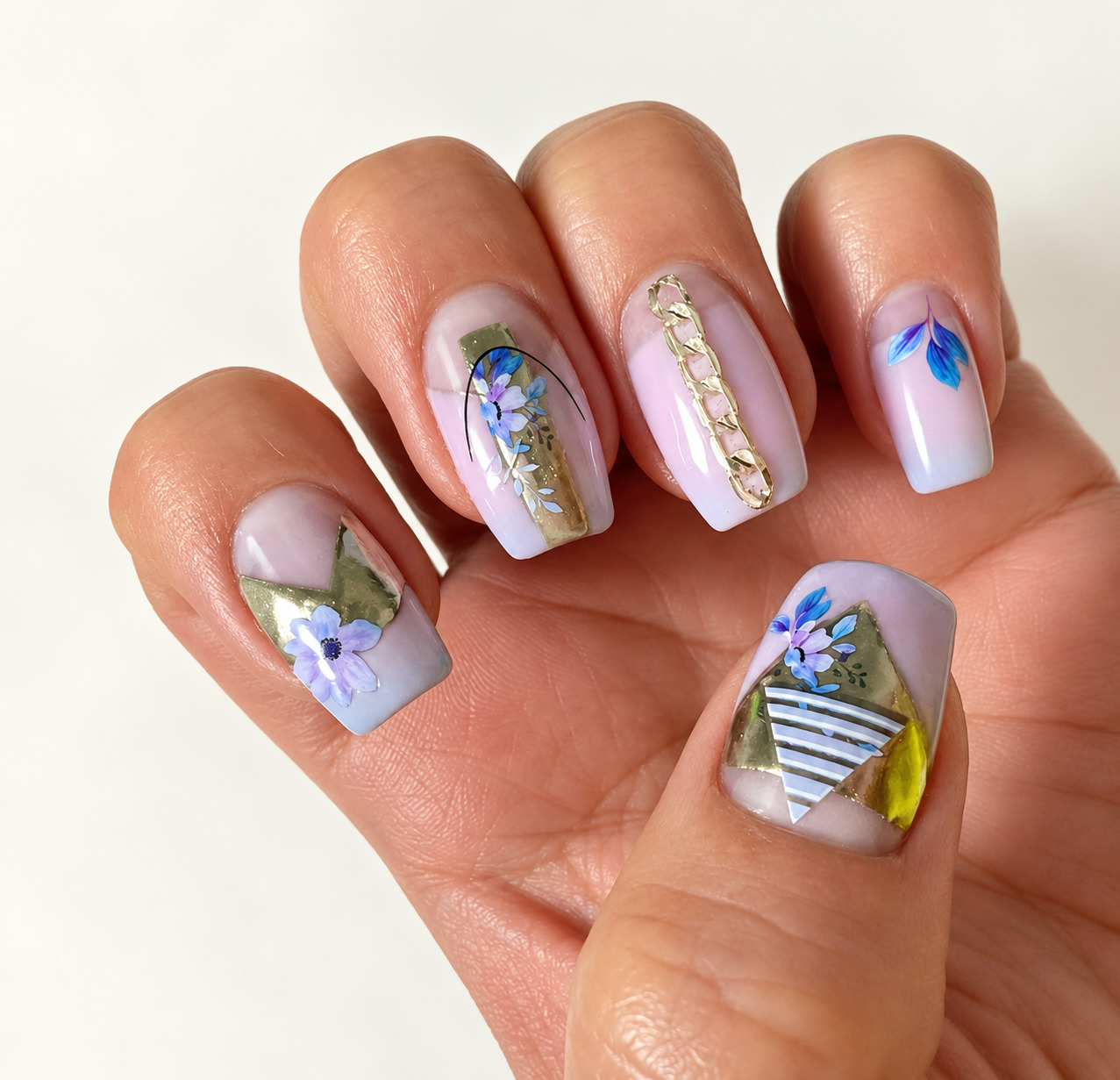 Close view of soft lavender square nails with flowers and gold foil accents