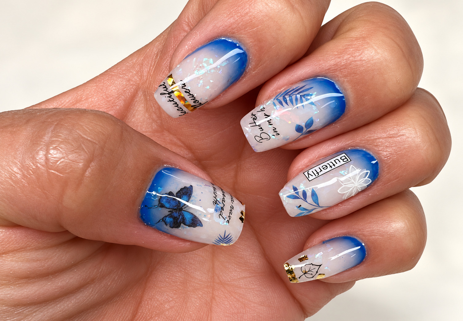 Blue gradient square nails with butterfly, botanical and foil details