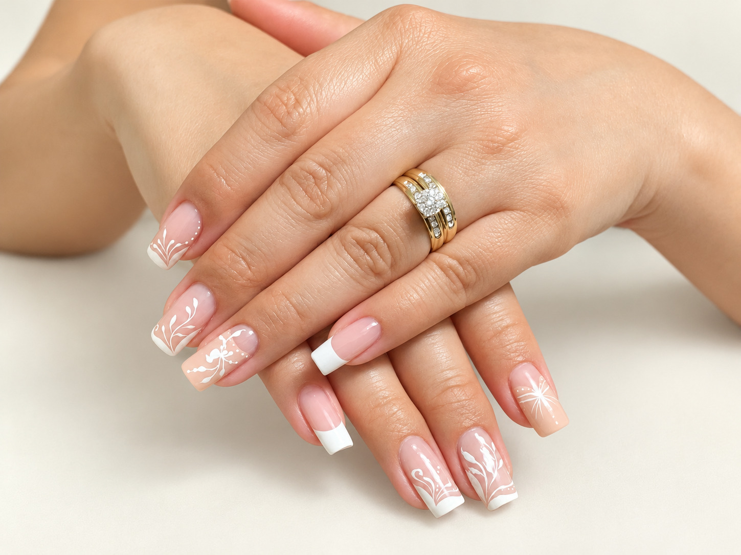 Two hands with white French square tips and delicate white botanical nail art