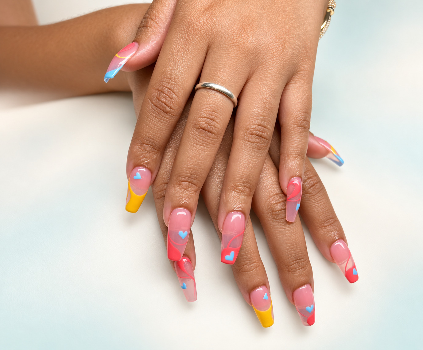 Long square nails with pink, yellow and aqua French tips, swirls and hearts