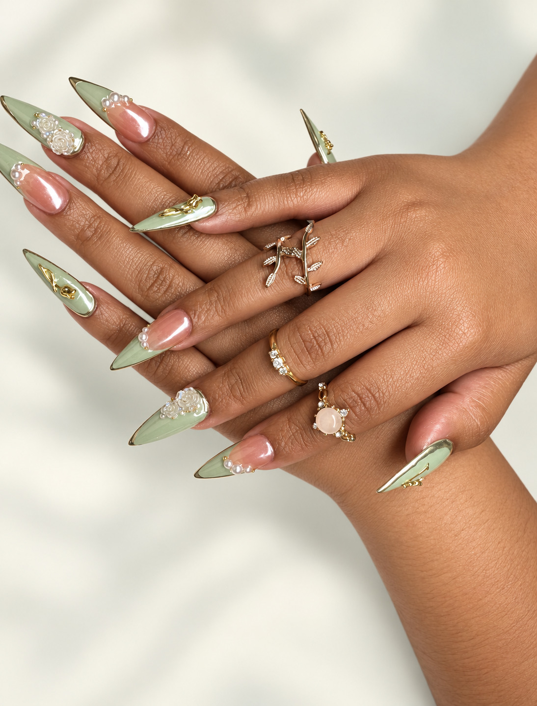 Sage green chrome stiletto nails with pearl and gold embellishments