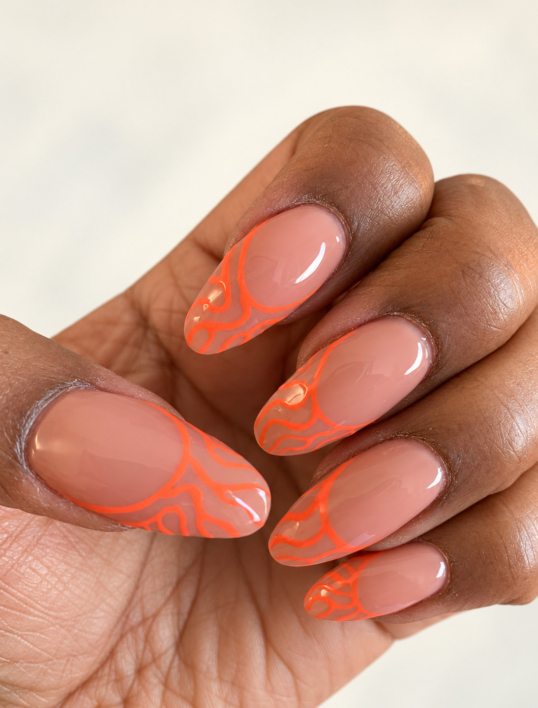 Sheer nude almond nails with fine orange flame outlines